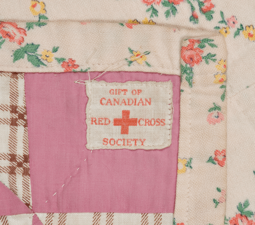 A photos of a label on the back of a quilt that reads Gift of Canadian Red Cross Society