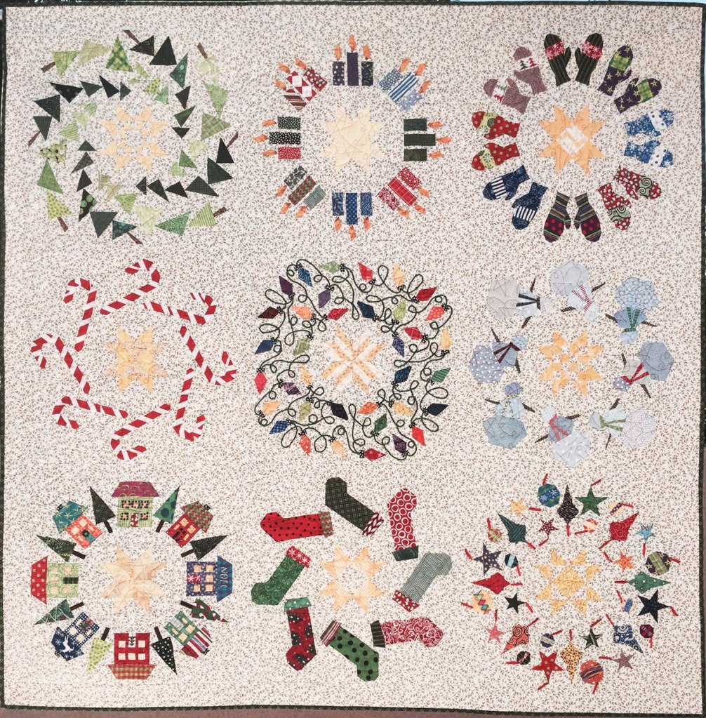 Photo of a quilt with six wreathes, all with Christmas motifs.